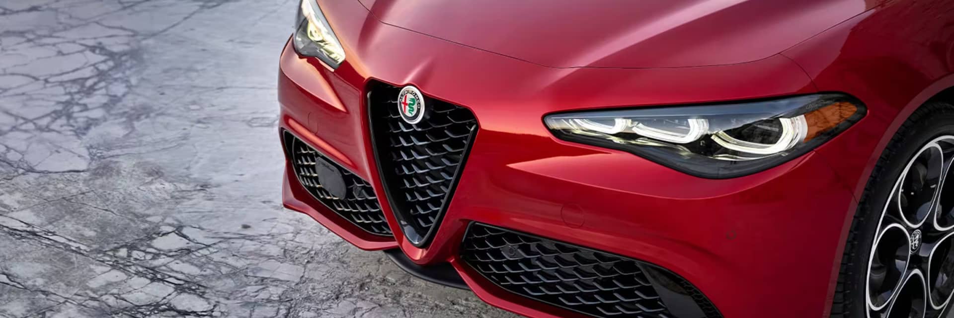 Angled close up view of the front of a red Alfa Romeo Giulia
