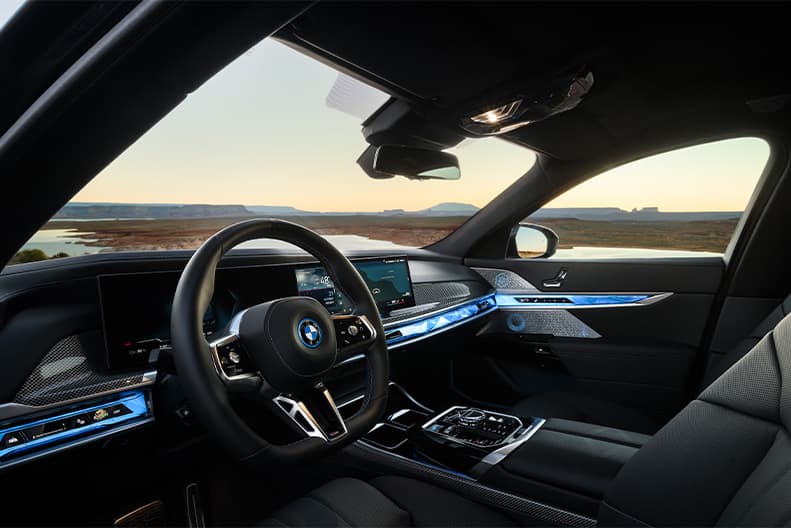 Dashboard view of a 2026 BMW i7 M70 parked in flat, desert landscape with the sun setting in the background.
