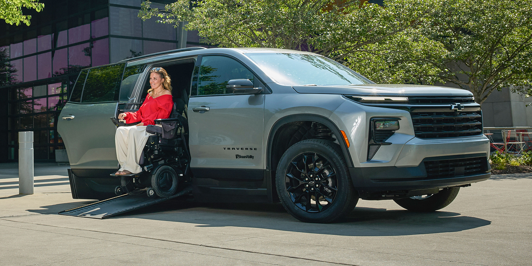 Chevy parked with woman exiting the vehicle via side door accessibility ramp.