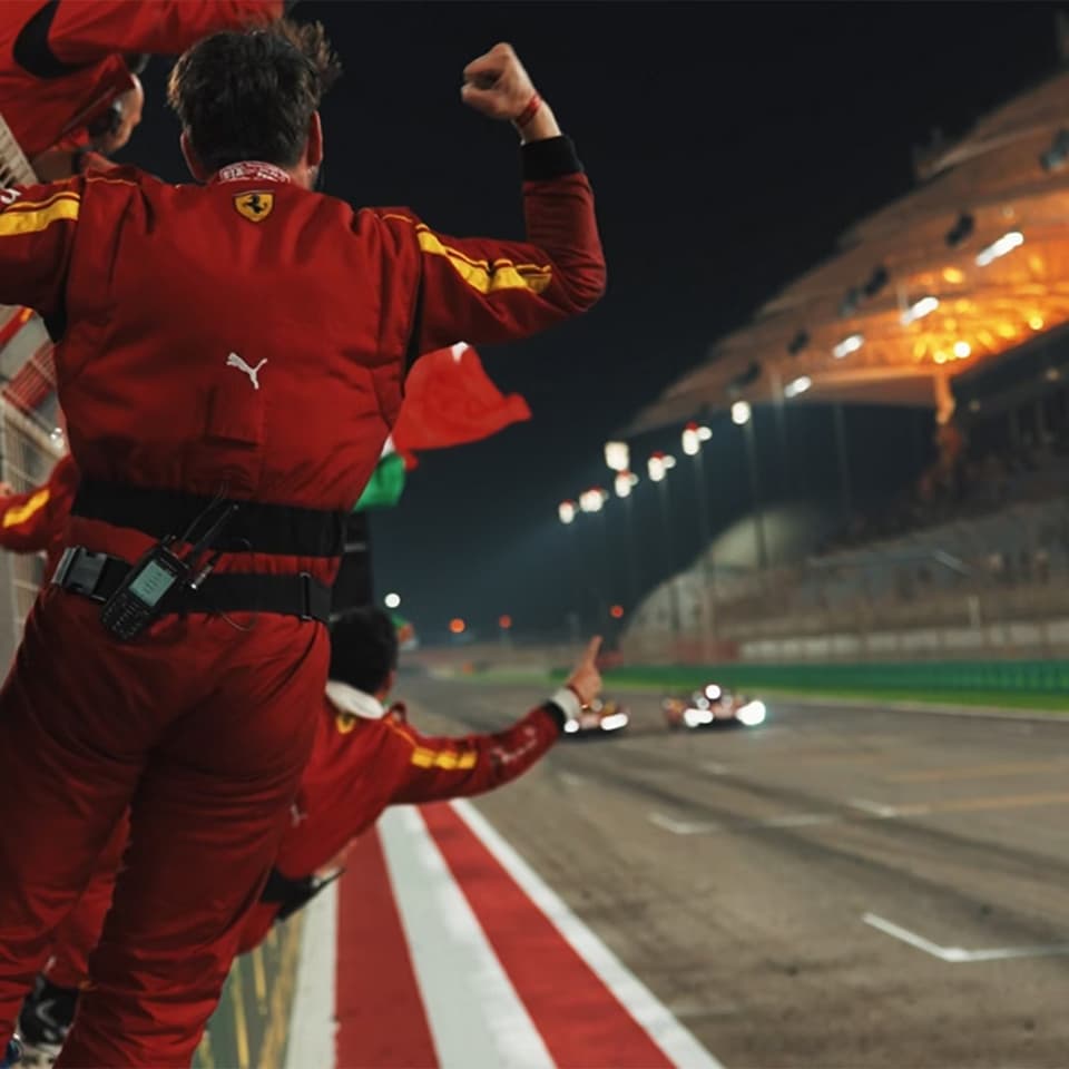 Ferrari pit crew celebrating on the sideline during a night race