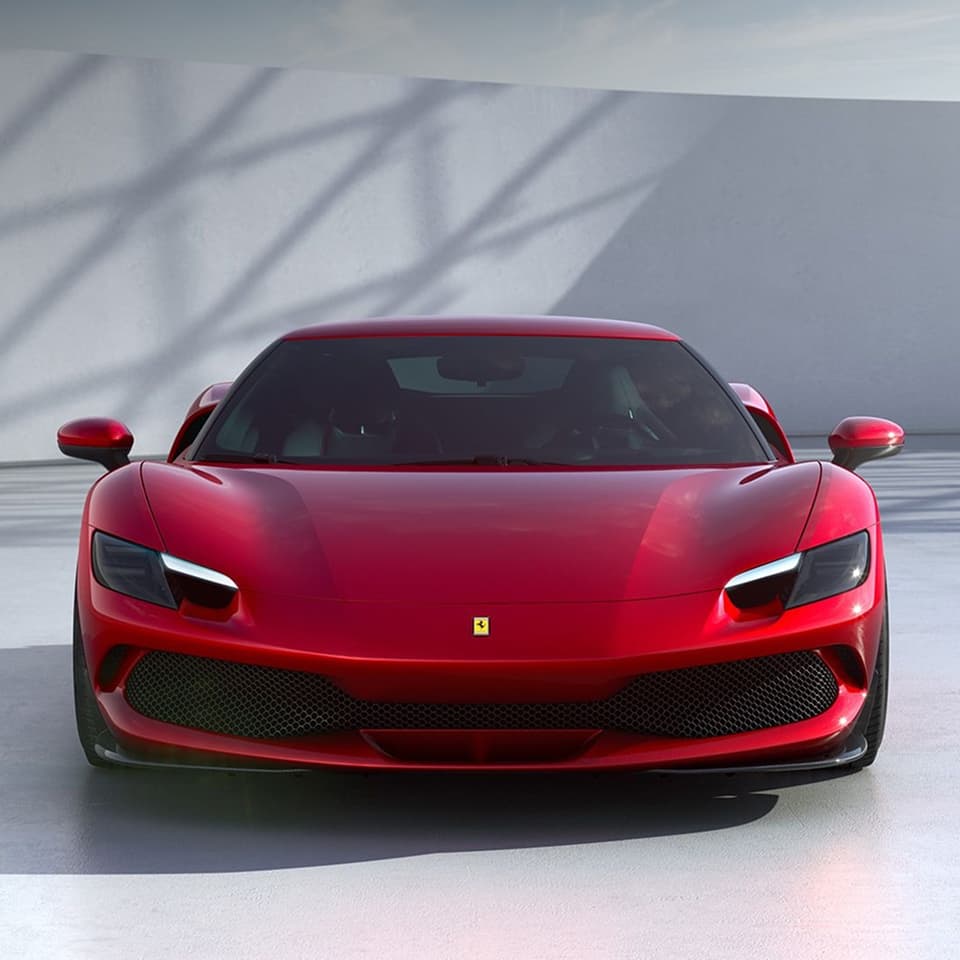 Red Ferrari sports car photographed head-on in a studio setting.