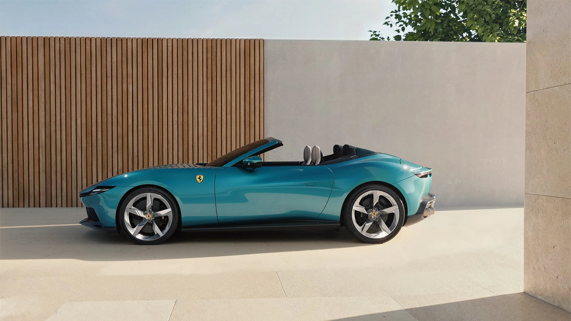Ferrari Amalfi Spider in teal, side profile view, parked against a wooden slat wall