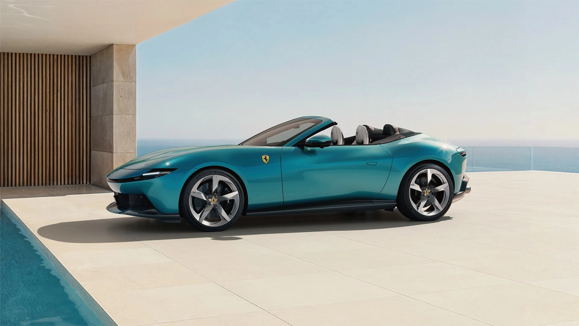 Ferrari Amalfi Spider in teal, side profile view, parked beside a pool with ocean backdrop