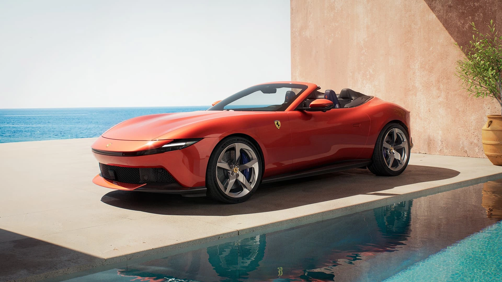 Ferrari Amalfi Spider in red, three-quarter front view, parked beside a pool with Mediterranean setting
