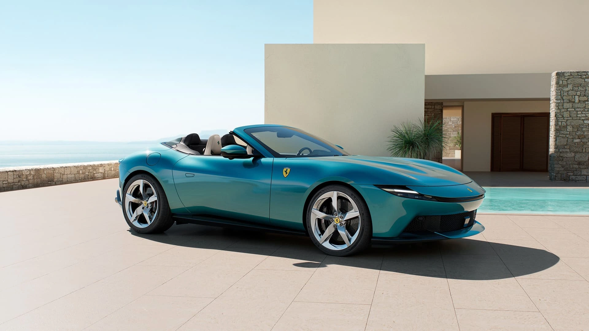 Ferrari Amalfi Spider in teal, three-quarter front view with soft top down, parked beside a pool