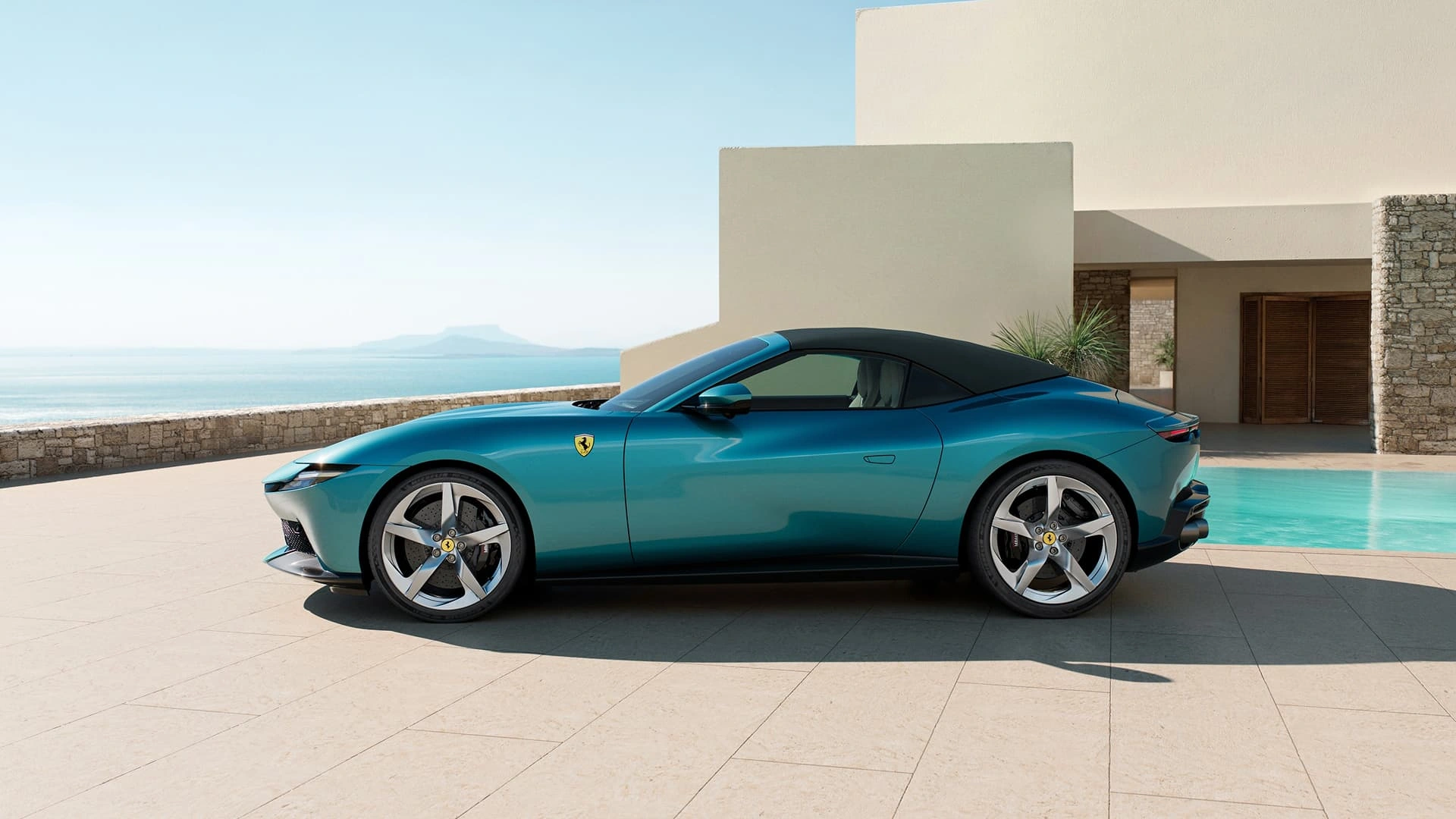 Ferrari Amalfi Spider in teal, side profile view with soft top up, parked beside a pool
