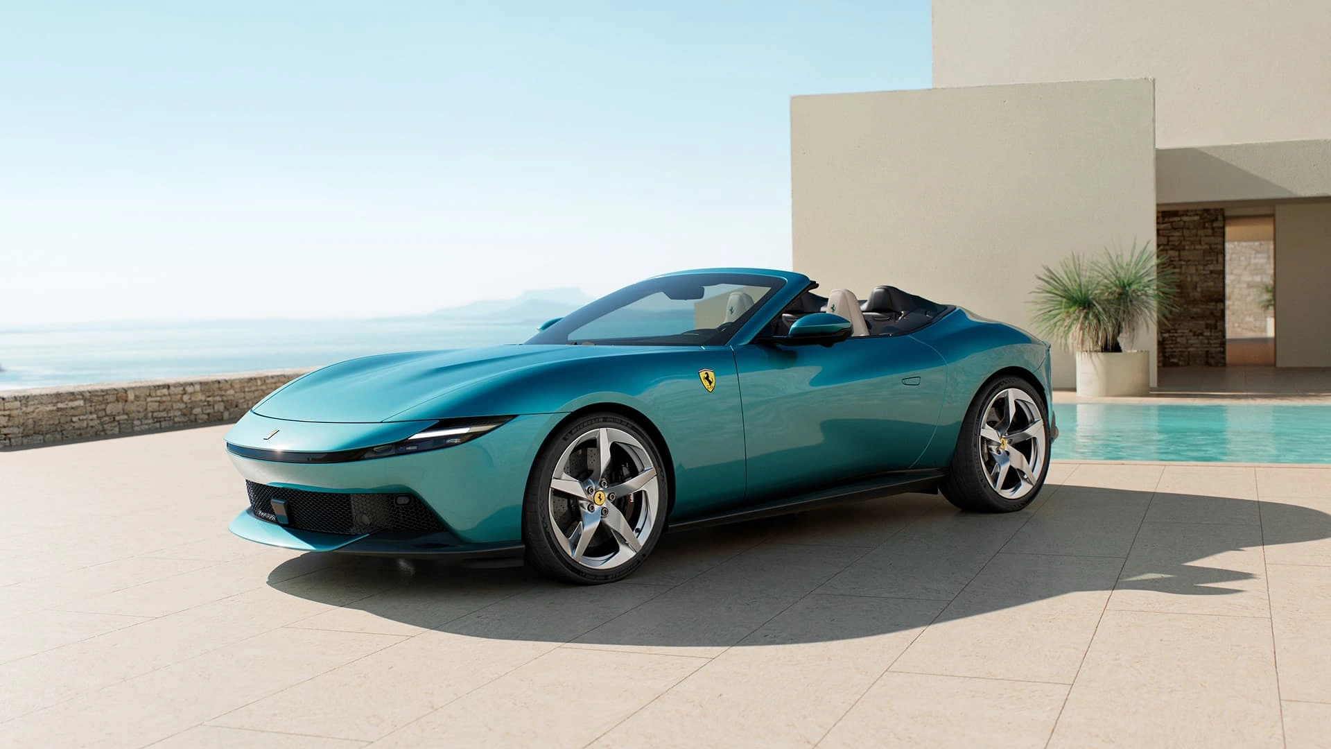 Ferrari Amalfi Spider in teal, three-quarter front view with soft top down, parked beside a pool