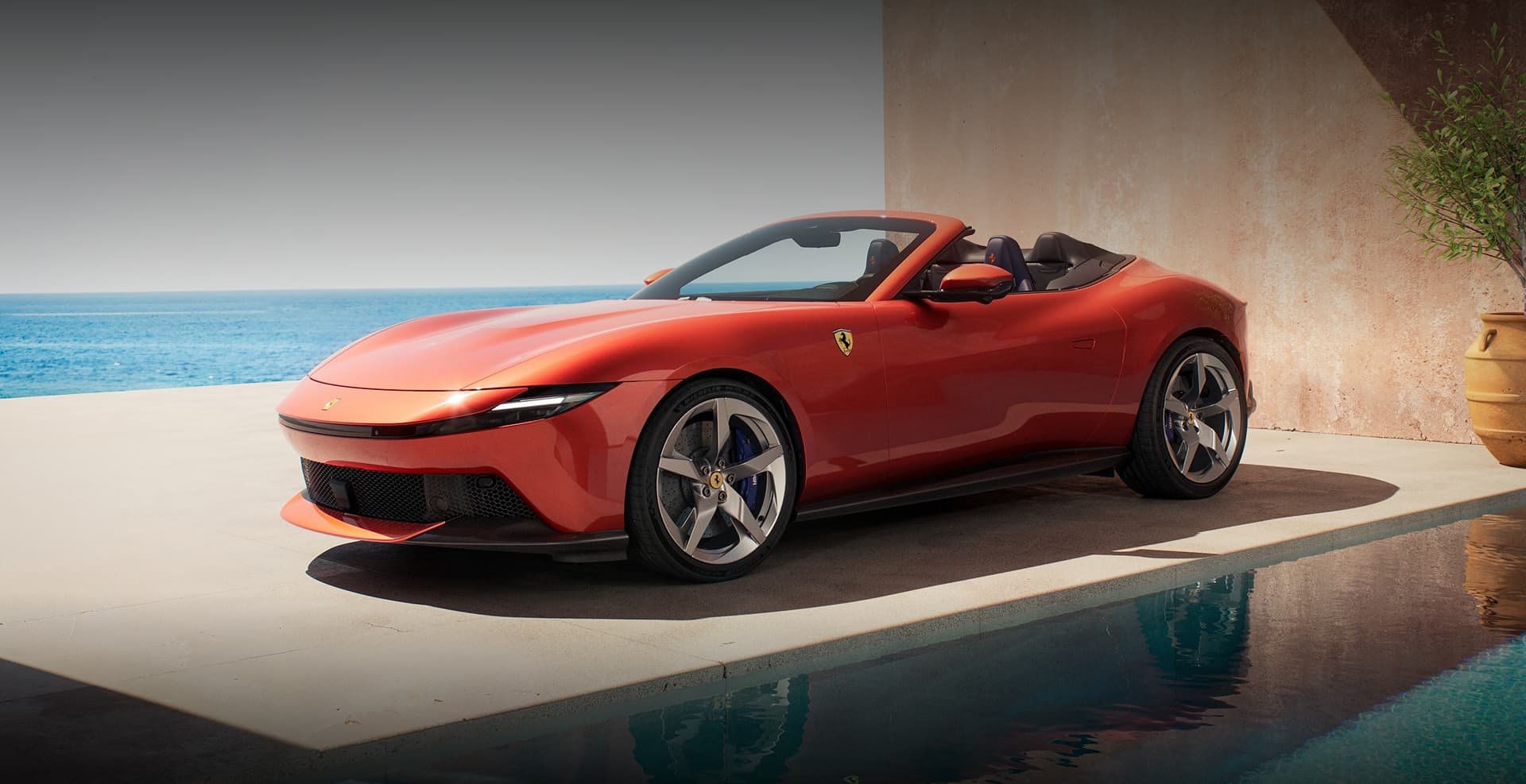 Red Ferrari Roma Spider convertible parked poolside with a coastal ocean view in the background.