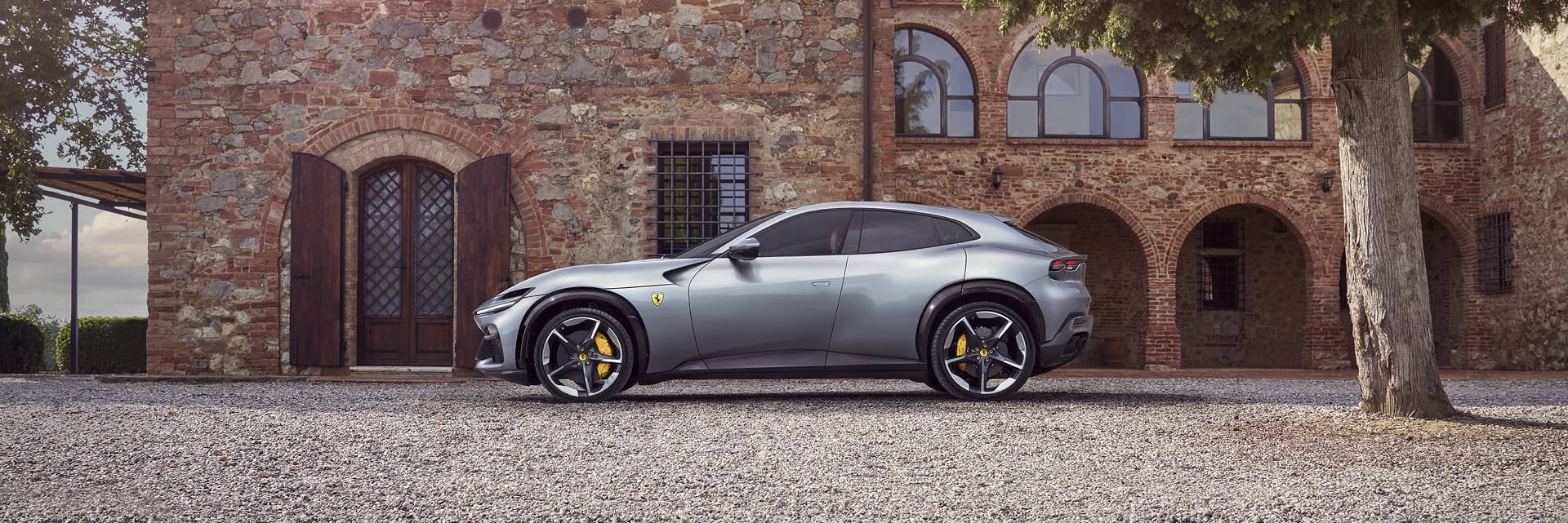 A sideview of a Ferrari parked in front of a building