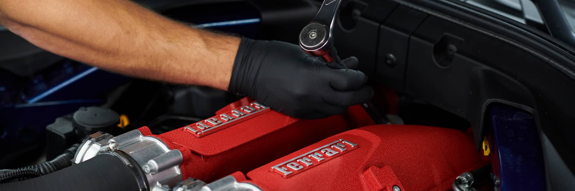 Gloved hands working in a Ferrari engine