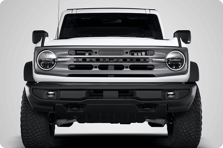 Front view of a white Ford Bronco with a dark grille and round headlights against a white background.