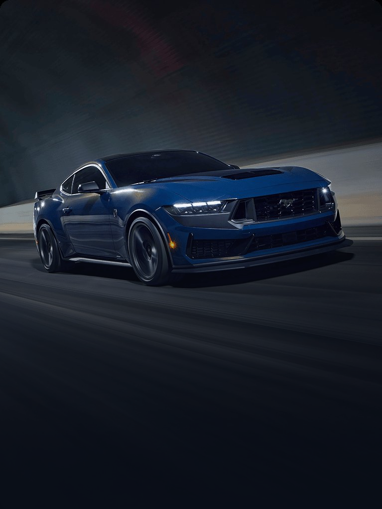 Dark blue Ford Mustang speeding on a track at night