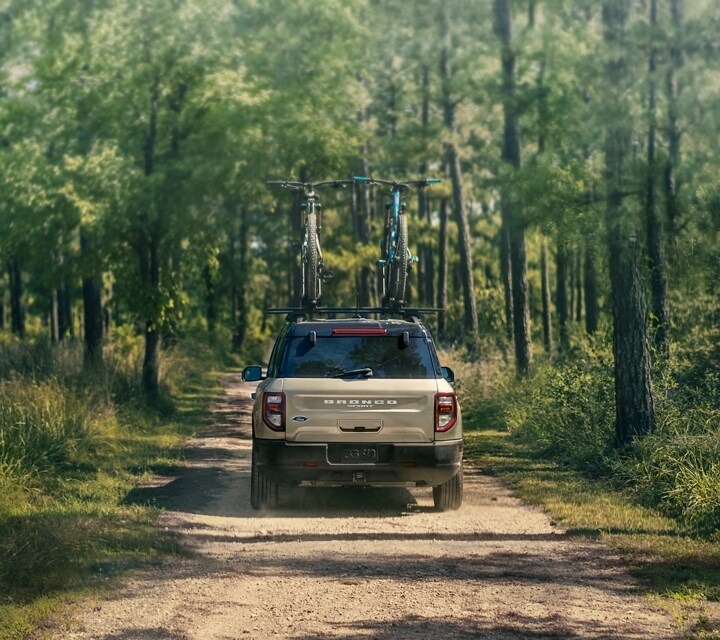 Ford Bronco Sport driving down dirt road surrounded by trees