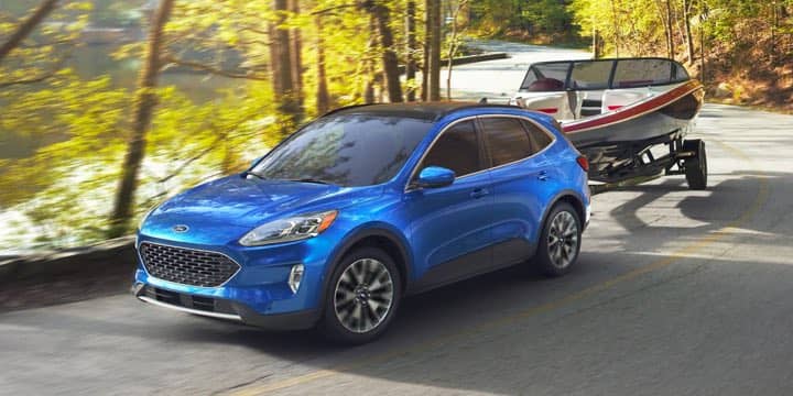 A blue Ford Escape pulling a boat.