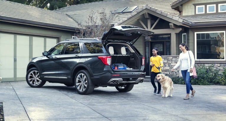 family and dog loading up the back for a Ford Explorer next to their home