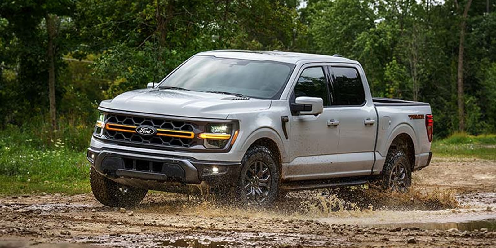 2025 Ford F-150® pickup driving through mud.