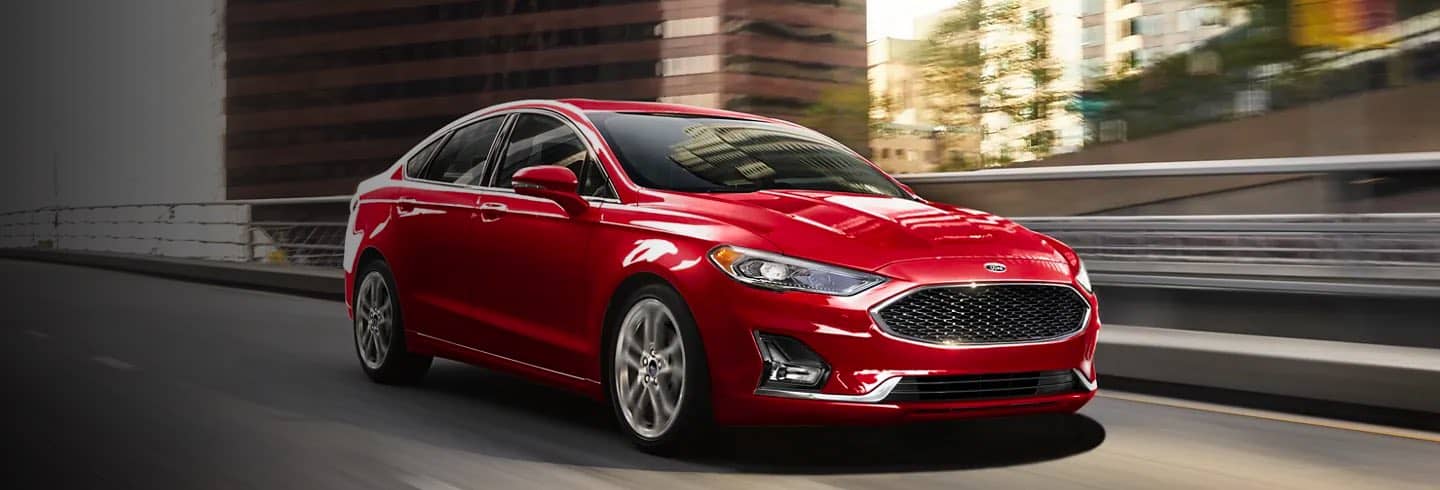 Red 2020 Ford Fusion Hybrid driving on a city street