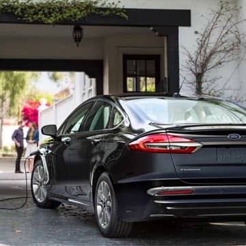 Rear view of a plugged-in Black Ford Fusion Hybrid