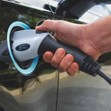 A person's hand plugging in a Ford Fusion Plug-in Hybrid