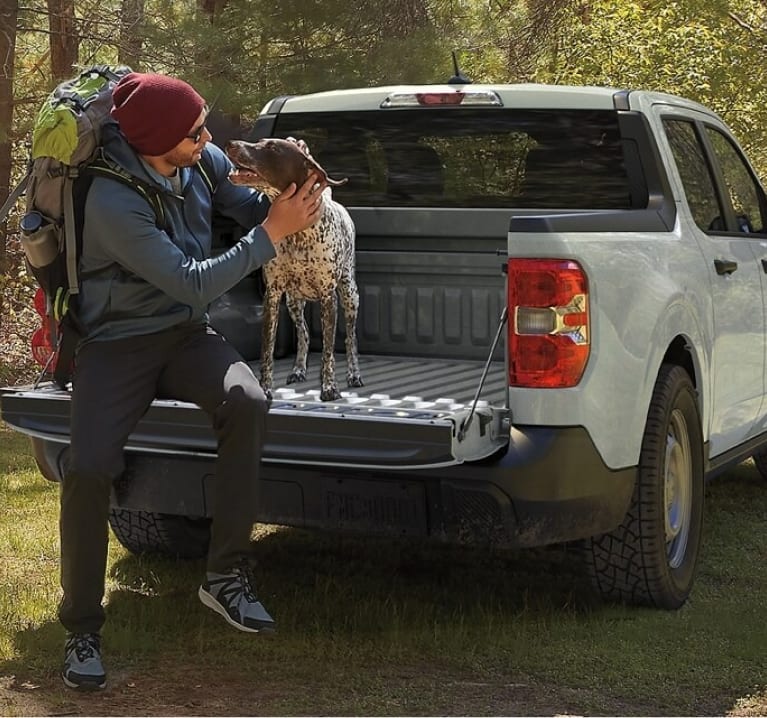 man sitting on the tailgate of a Maverick petting his dog