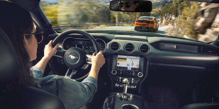 Interior view of a Ford Mustang driver following another Ford Mustang
