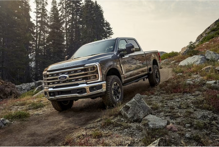 Super Duty driving down a slightly curved hill with rocky outcrop and forestry background