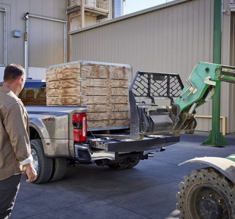 workers loading a pallet into the bed of a Ford Super Duty