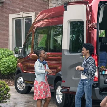 A Red Ford Transit Van parked with rear doors open in a driveway.