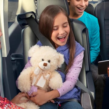 A child holding a teddy bear while sitting in a Ford Transit Van
