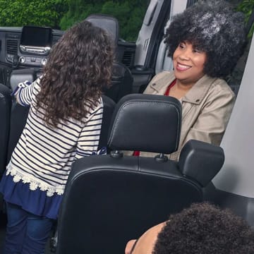 A women smiling looking at a child in the passenger seat of a Ford Transit Van.