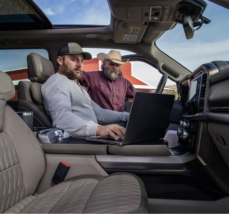 Two men looking at laptop on center console