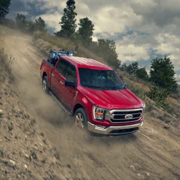 Red Ford F-150 driving down hill.