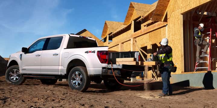 White Ford F-150 loading lumber and tools at a construction site