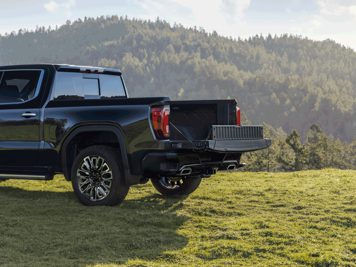Sierra EV Denali parked on a hill overlooking an ocean with tailgate down