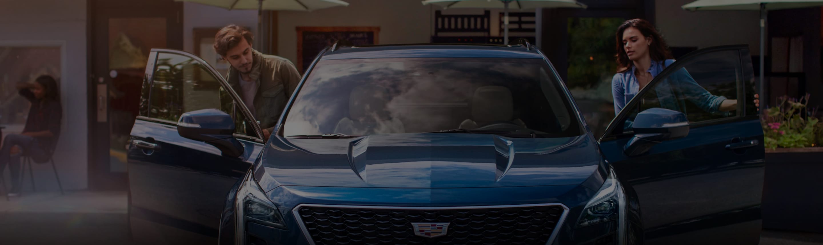 A couple getting inside a blue Cadillac Sedan infront of a store