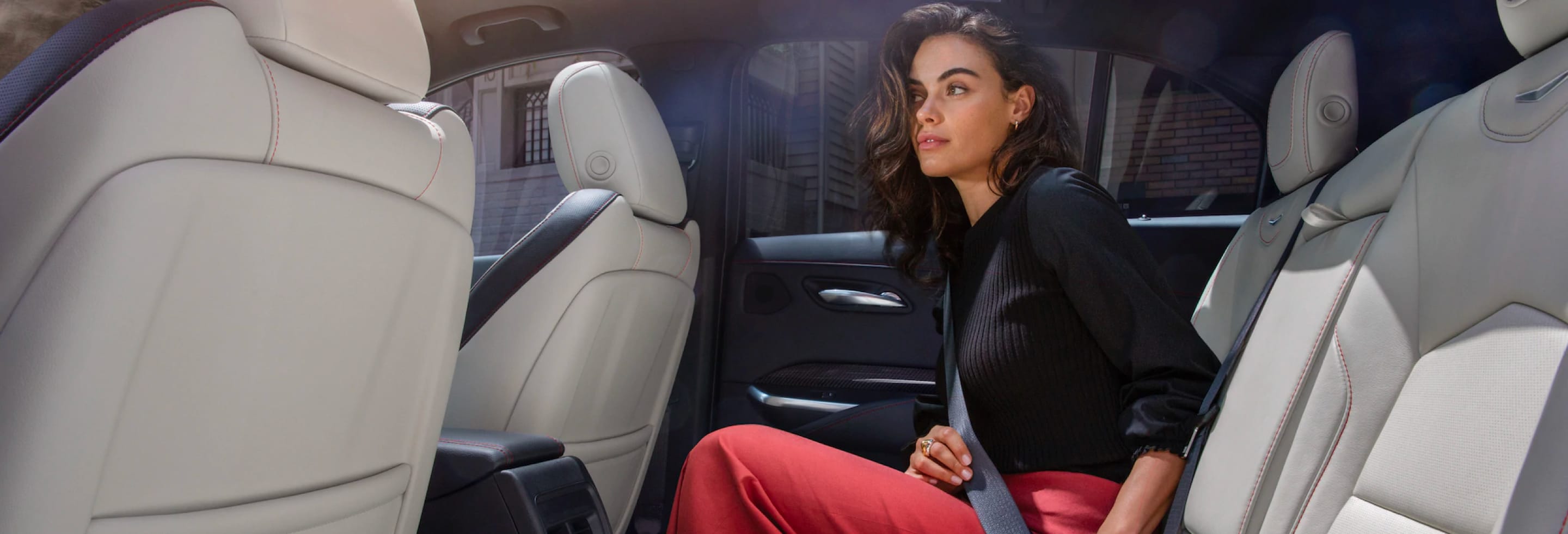 Lady buckling her seatbelt in the second row in a sedan.