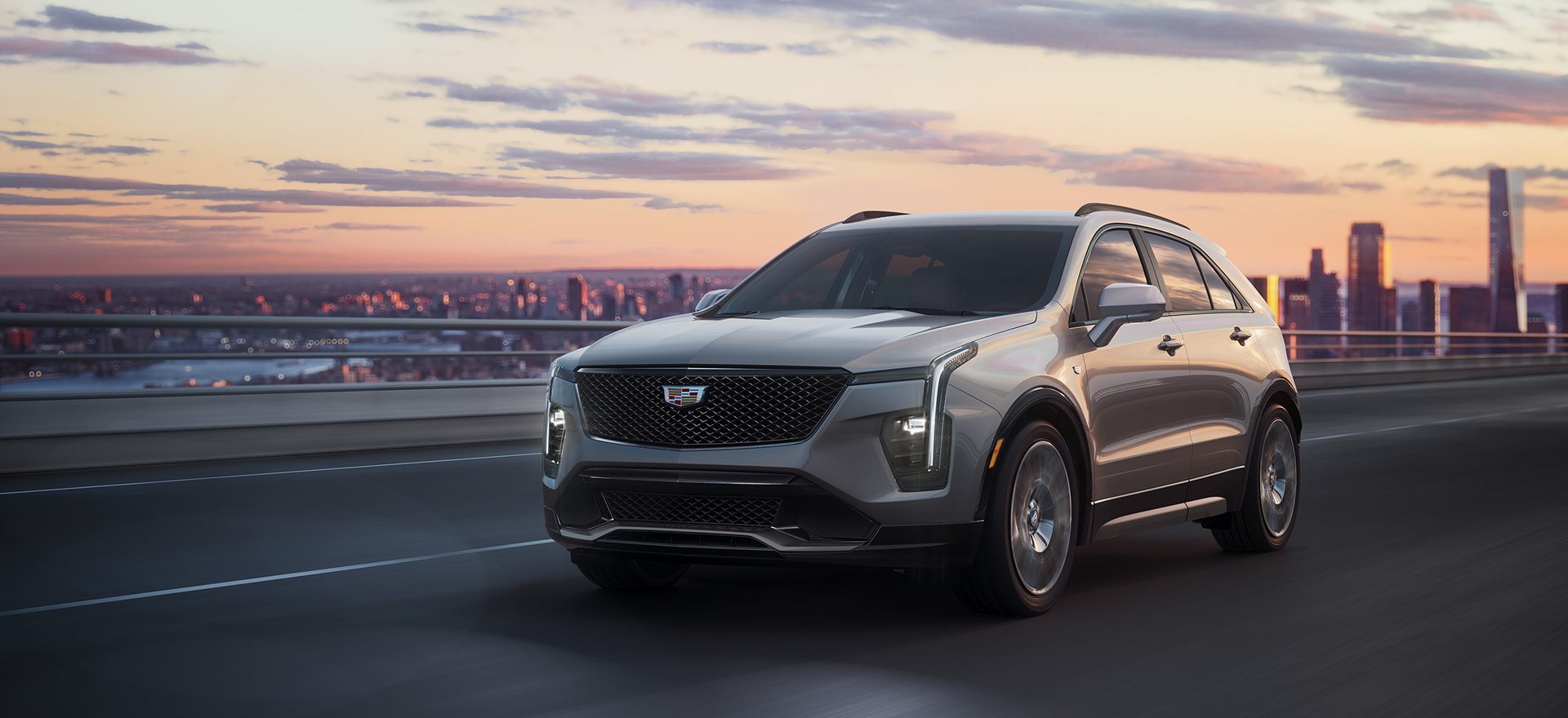 Cadillac SUV driving with a city in the background