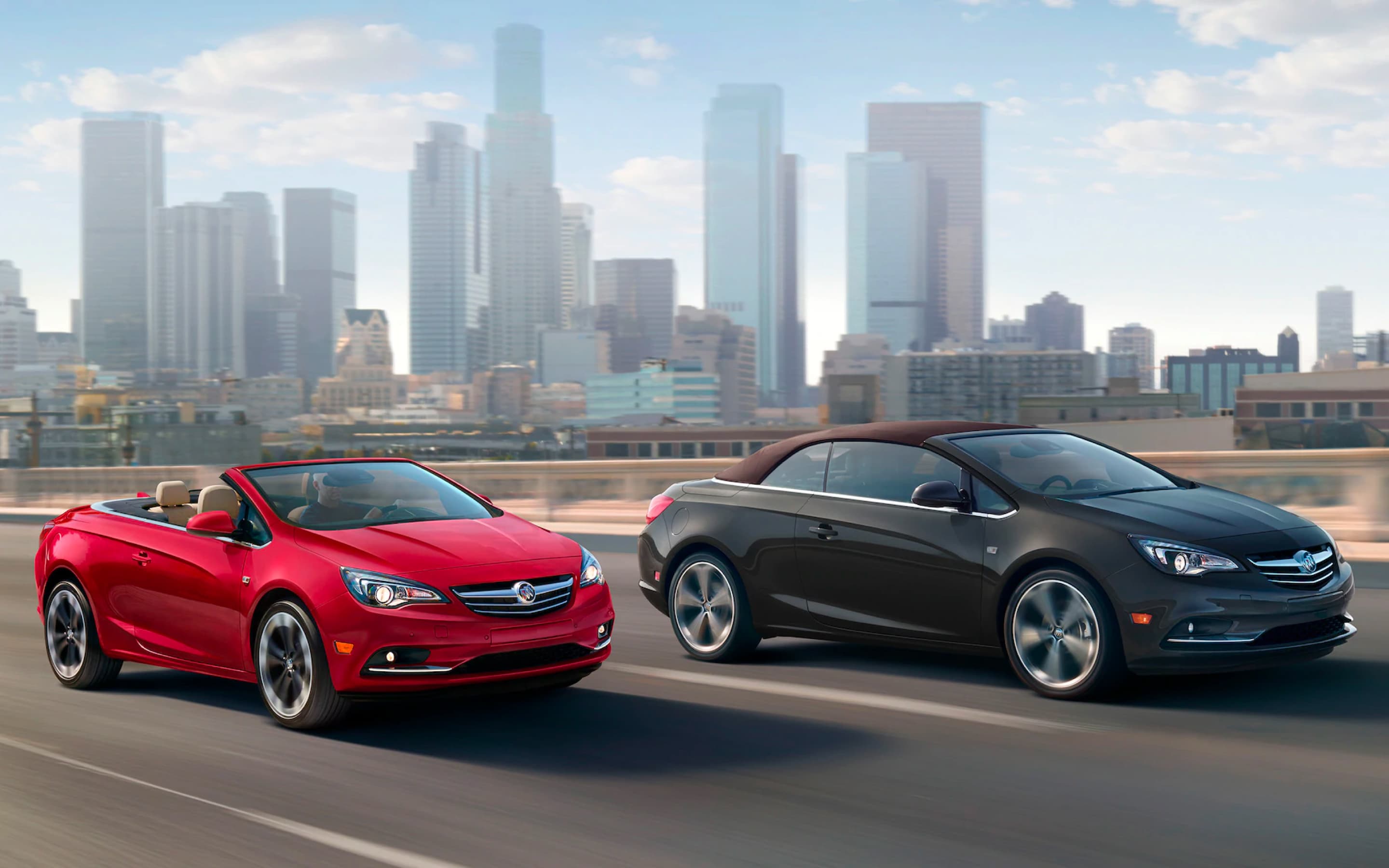 A red and blue Cascada driving side by side on the highway.