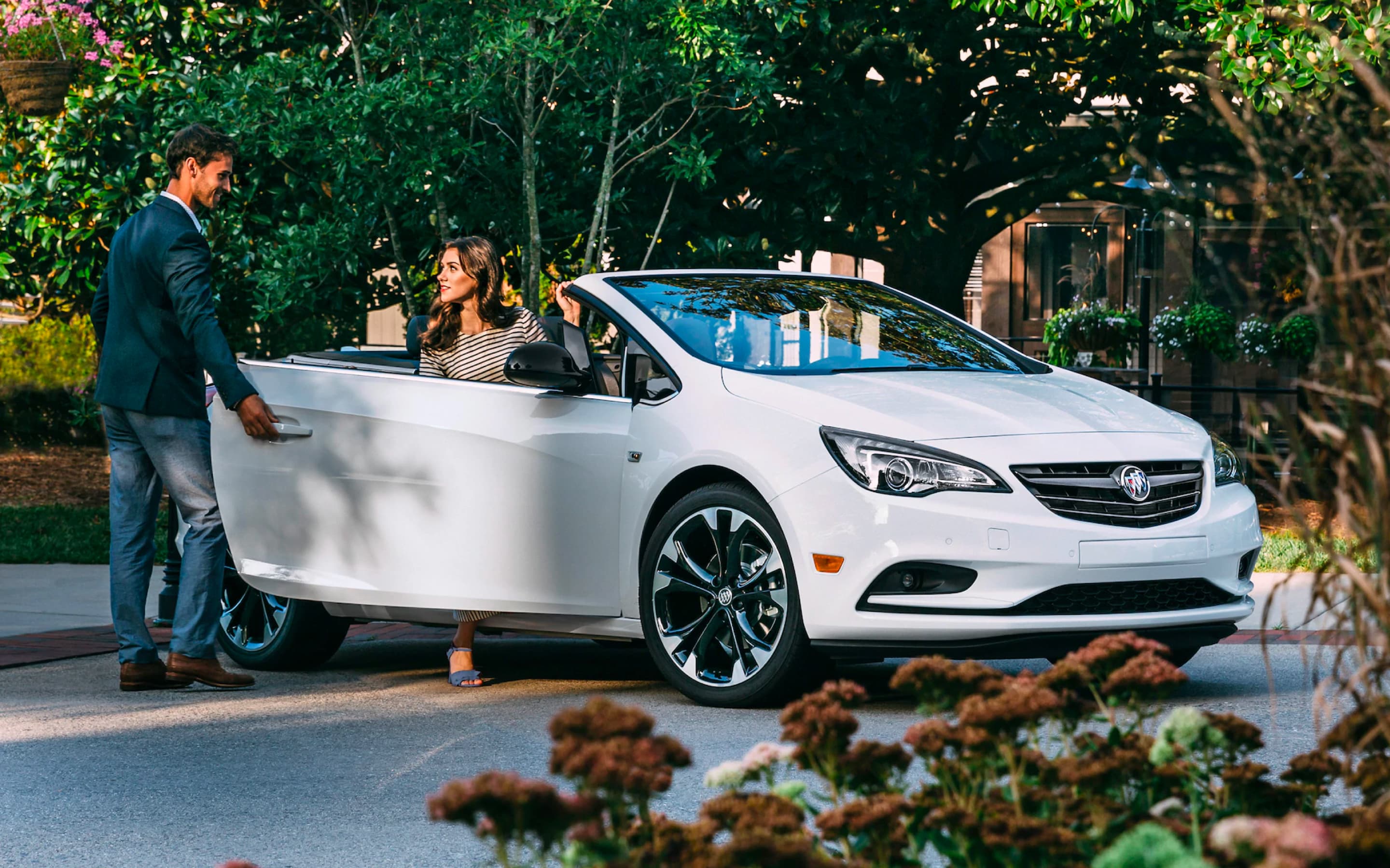 A man opening the door of a white Cascada to a lady