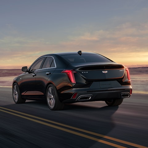 Three Quarters Rear View of a Black 2026 CT4 Driving Down a Desert Road