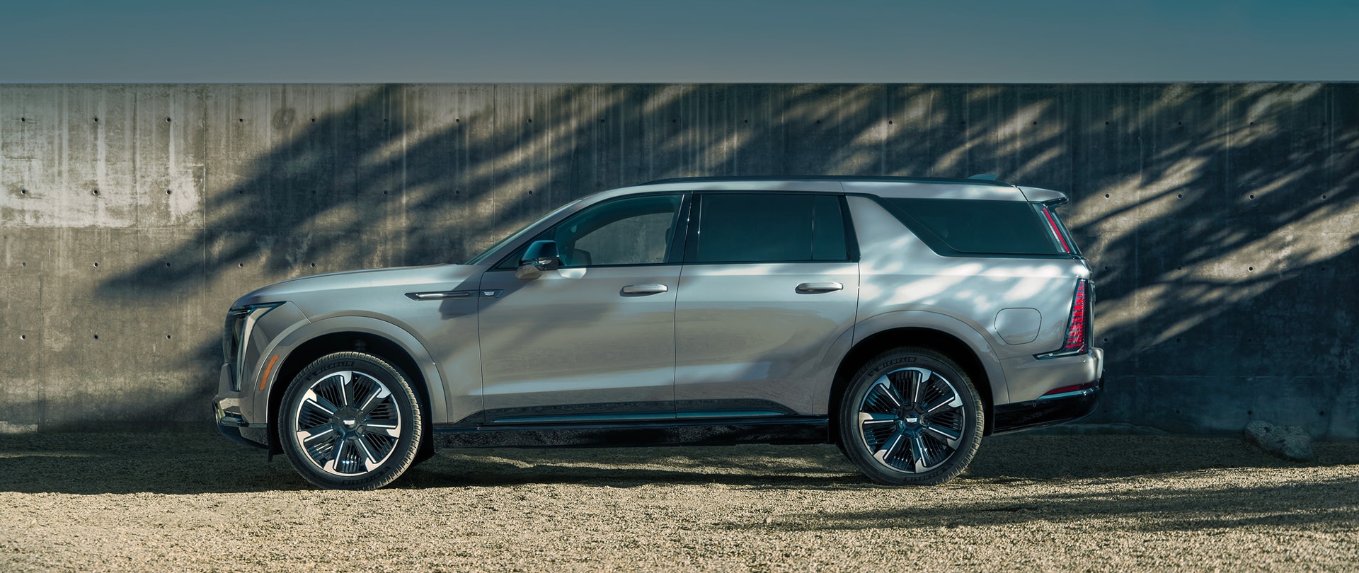 2026 Cadillac Escalade IQL parked near a wall shaded by tree branches