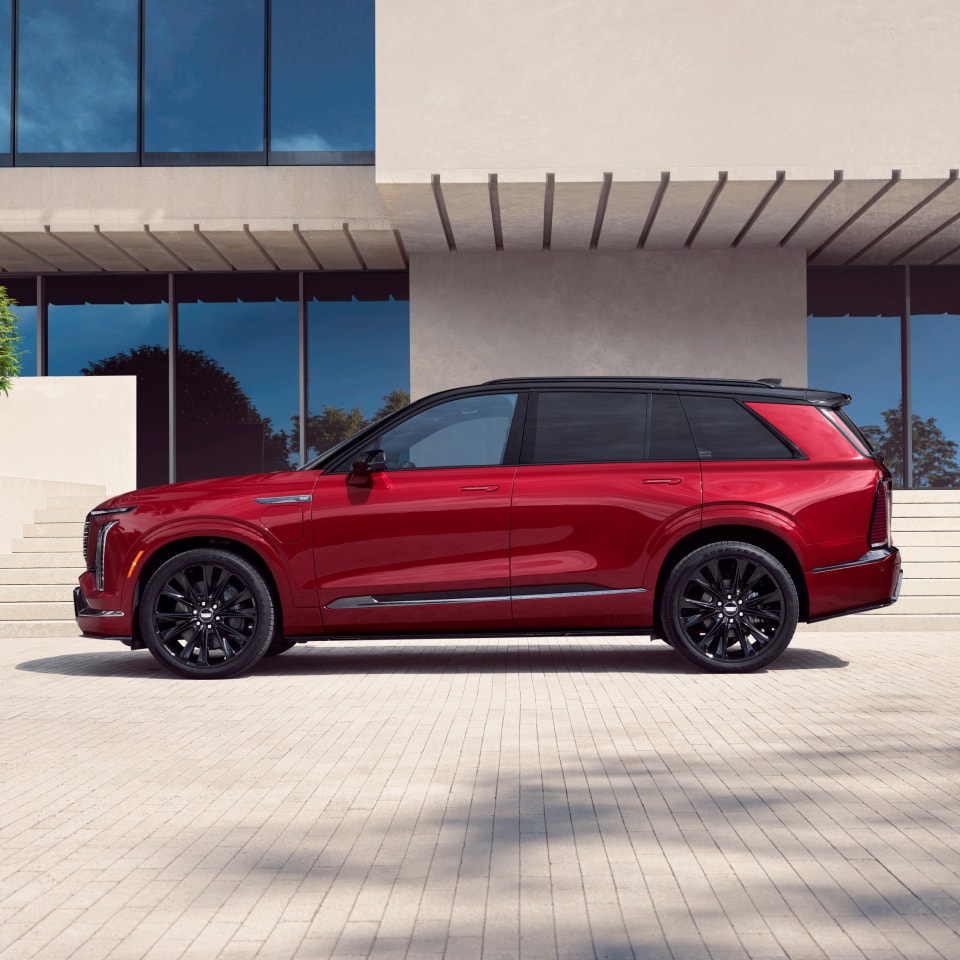 Profile View of the Red Cadillac VISTIQ Parked on a White Brick Driveway Outside a Modern Home