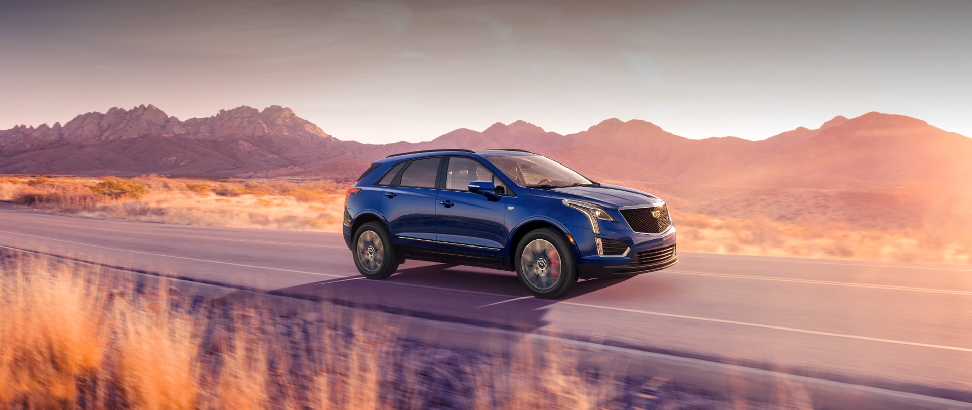 The 2026 Cadillac XT5 Driving Through a Western Landscape During Golden Hour
