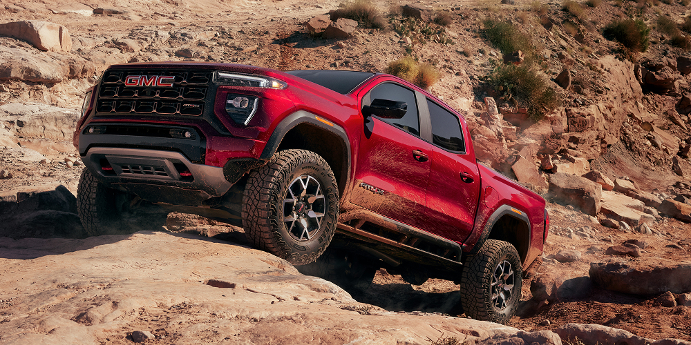 A Red GMC Canyon AT4X Pickup Truck Navigating Rocky Off-Road Terrain in a Desert Landscape