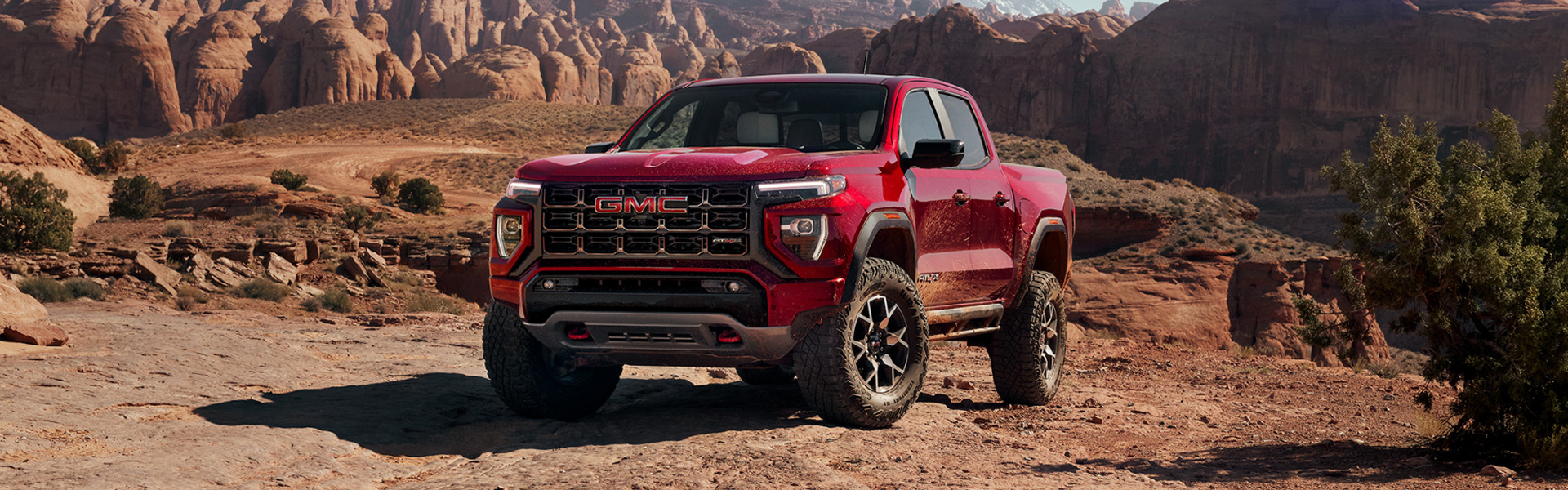 A Red GMC Canyon AT4X Truck on Rocky Desert Terrain with Rock Formations and Mountains