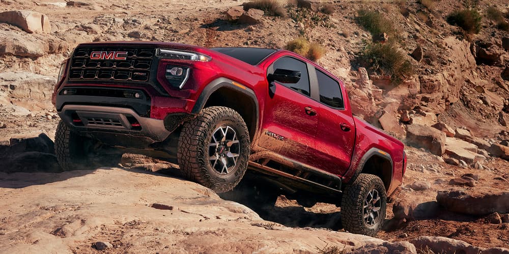 Red 2026 GMC Canyon climbing over rocky terrain