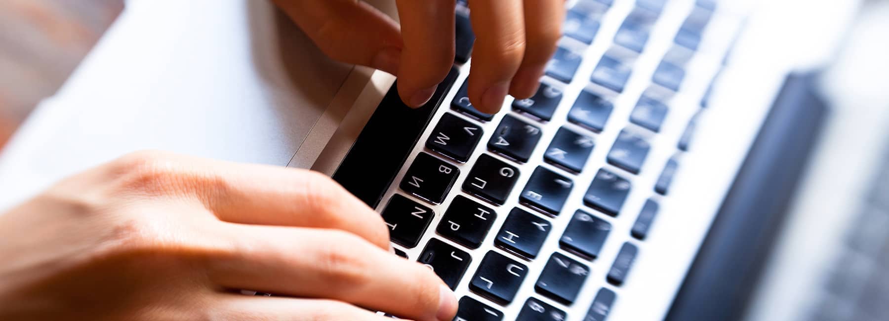 Fingers typing on a laptop computer