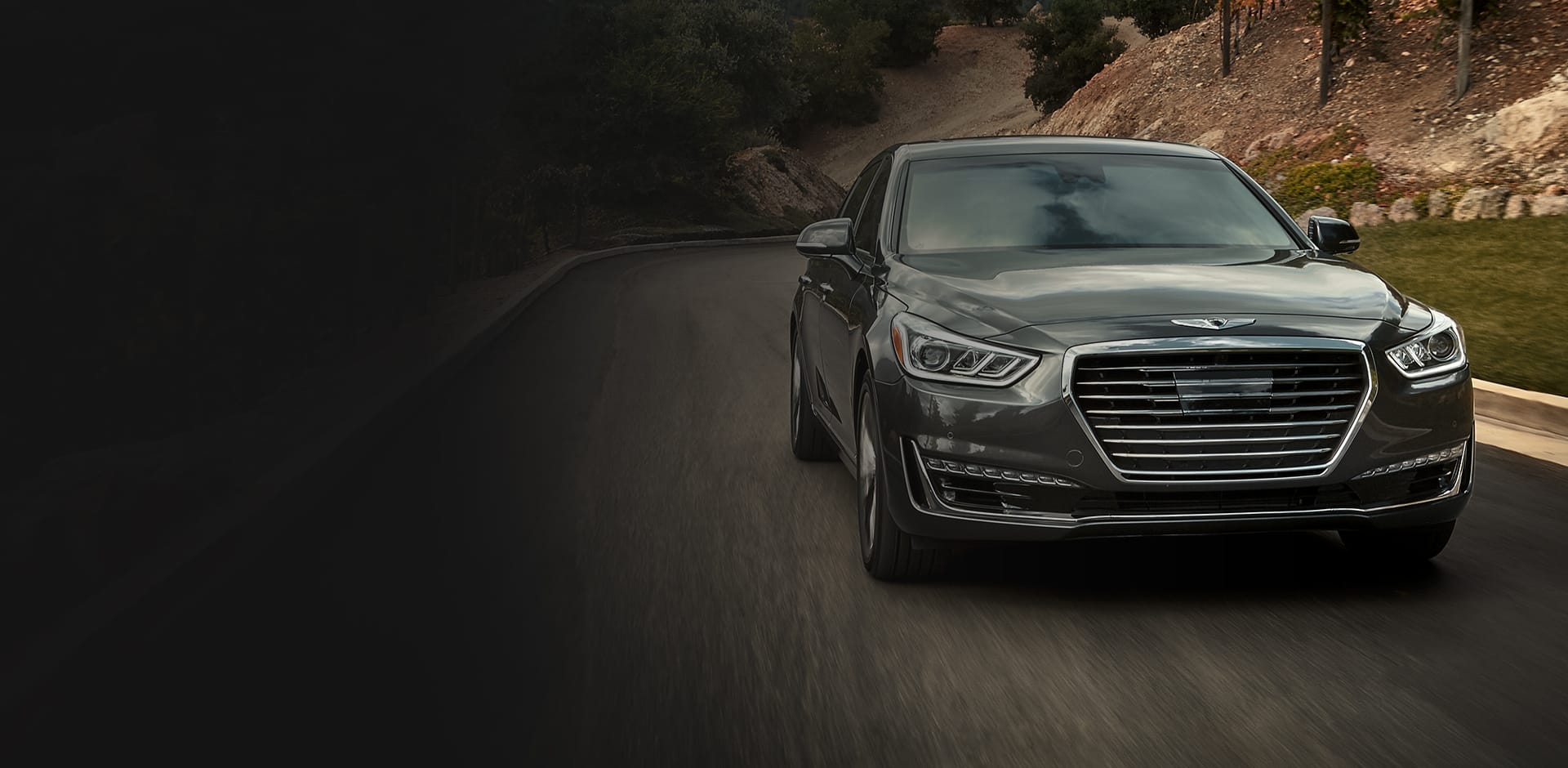 A Genesis sedan driving through a mountainous road