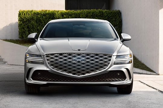Front view of grille details on Genesis G80 in Ceres Blue parked in front of modern house