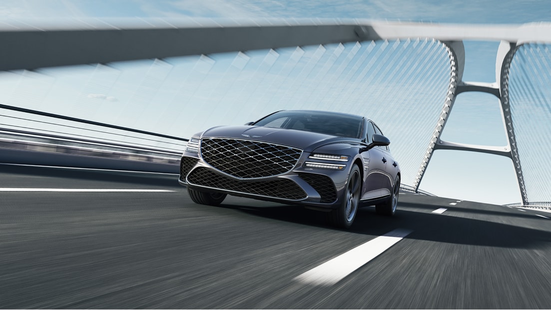 Low 7/8 front driver side view of Genesis G80 in Ceres Blue driving on suspension bridge